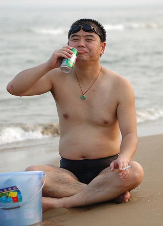 Chinese guy drinking beer on beach